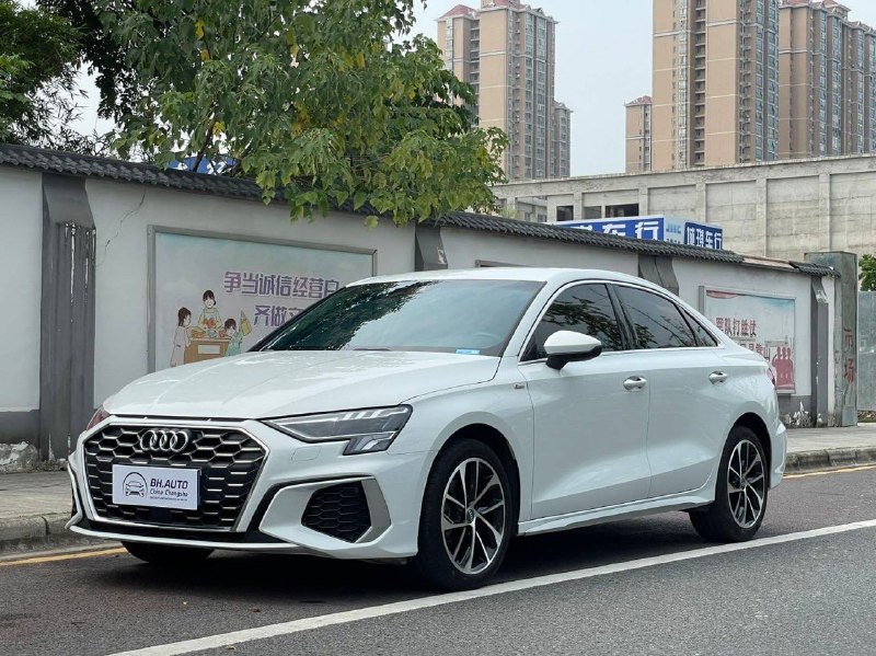 Белый Audi A3L на городской улице, вид спереди и сбоку