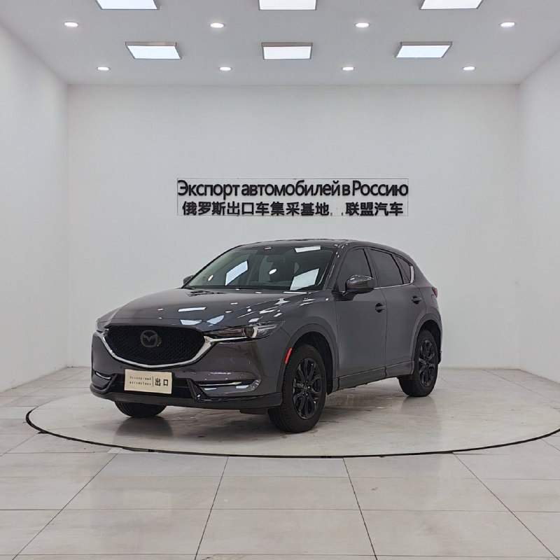Серая Mazda CX-5 спереди и сбоку в светлом выставочном зале